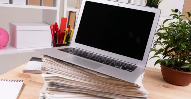 Laptop on top of pile of paperwork