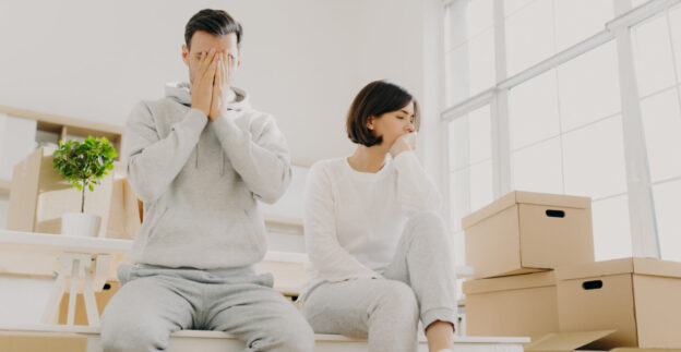 Stressed couple sitting with moving boxes
