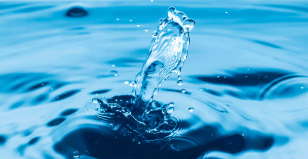 Water drop making splash in pool of water